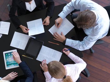 Several people all working around a table using tablets